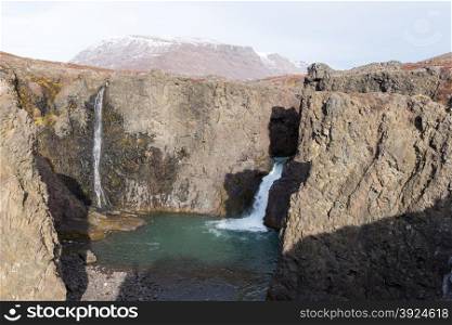 Waterfall and landscape in Greenland. Waterfall and arctic landscape in a rocky environment on Disko Island in Greenland