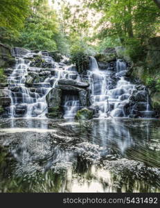 Waterfall cascades flowing over flat rocks in forest landscape