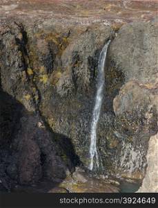 Waterfall. Closeup of a high waterfall in a rocky environment on Disko Island in Greenland
