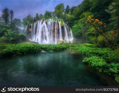 Waterfall in green forest in Plitvice Lakes, Croatia at sunset in summer. Colorful landscape with fall, blooming park, trees, water lilies, river in spring. Scenery. Park in woods at dusk. Nature 