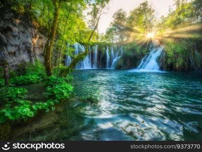 Waterfall in green forest in Plitvice Lakes, Croatia at sunset in summer. Colorful landscape with fall, blooming park, trees, water lilies, sunbeams, river in spring. Scenery. Park in woods. Nature 