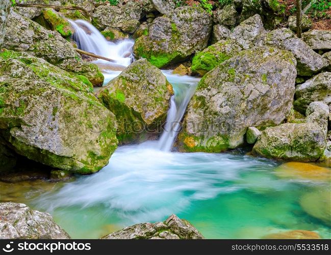 Waterfall in mountain rainforest with turquoise lagoon