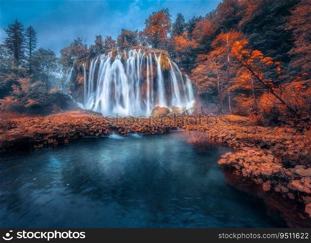 Waterfall in red forest in Plitvice Lakes, Croatia at sunset in autumn. Colorful landscape with fall, park, trees, orange foliage, water lilies, river. Scenery. Park in woods at dusk. Nature 