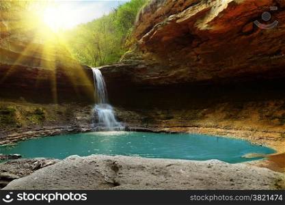 Waterfall in the mountains illuminated by the sun