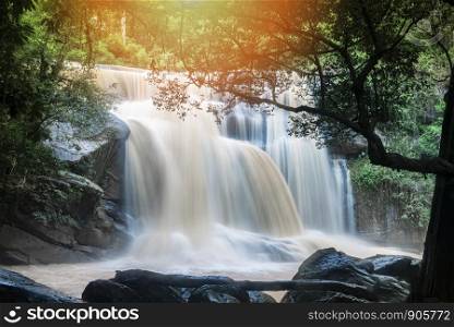 Waterfall landscape beautiful with sunlight rays in the river stream on the mountain with tree and the rock stone foreground / waterfall thailand tropical forest