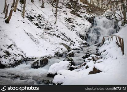 Waterfall mountain river in a forest in winter. Waterfall mountain river
