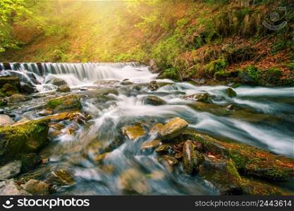 Waterfall on a mountain river in the autumn forest under the bright sun. Waterfall on a mountain river in the autumn forest under bright sun