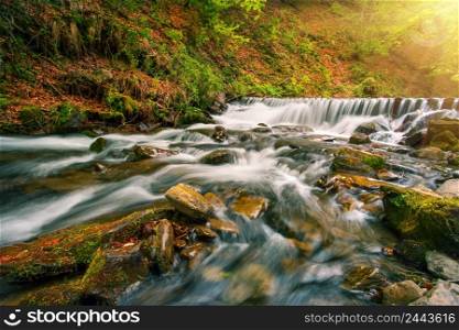 Waterfall on mountain river in the autumn forest under the bright sun. Waterfall on mountain river in autumn forest under bright sun