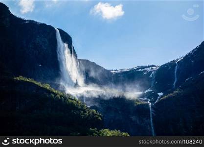 Waterfalls cascading down steep cliffs under blue sky near the Sognefjord in Norway.