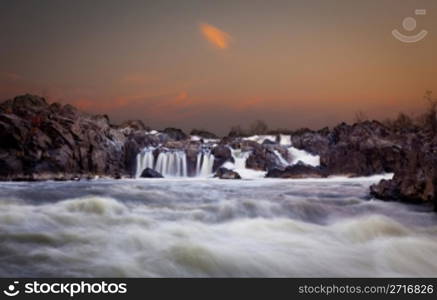 Waterfalls on the Potomac river near Washington DC after sunset as the setting sun illuminates the clouds over Great Falls