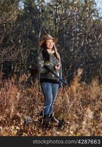 Waterfowl hunting, the female hunter carry a shotgun, autumnal bushes on background