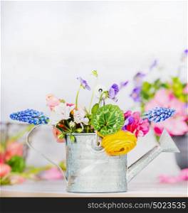 Watering can with colorful garden flowers on table, front view, gardening concept