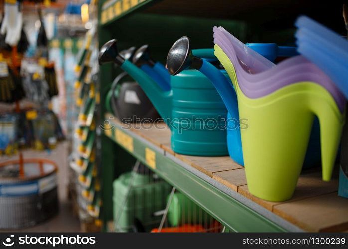 Watering cans assortment on the shelf, shop for floristry, nobody. Equipment in store for floriculture, florist instrument choice, gardening hobby tools