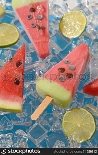 Watermelon, fruit popsicle and lime slices on ice cubes