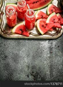 Watermelon juice in bottles on a steel tray. On a rustic background.. Watermelon juice in bottles on a steel tray.