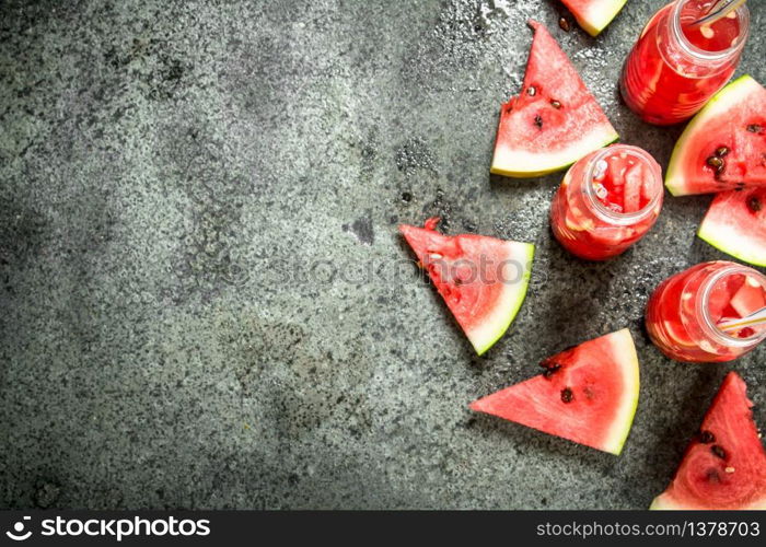 Watermelon juice in bottles with straws. On a rustic background.. Watermelon juice in bottles with straws.