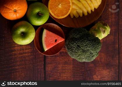 Watermelon, pineapple, oranges, cut into pieces with avocado, Broccoli and apples on wood table. Top view.