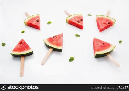 Watermelon slice popsicles and paper mint on white wooden background.