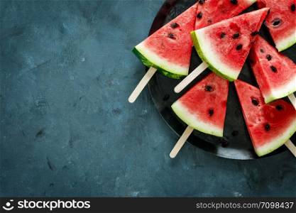 Watermelon slice popsicles on a blue background, top view