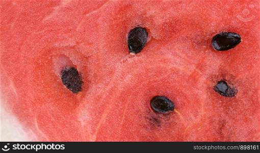 Watermelon texture close up. Background of Watermelon with seeds. Close up of juicy and sweet flesh watermelon with black grains. Watermelon texture close up.