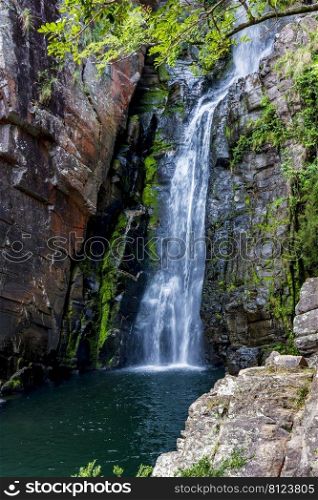 Waters of waterfall called Veu da Noiva between moss covered rocks and the vegetation of an area with nature preserved in the state of Minas Gerais, Brazil. Waters of waterfall called Veu da Noiva between moss covered rocks and the vegetation