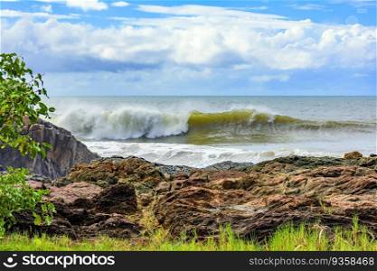Wave breaking behind the rocks in Serra Grande on the rocky coast of Bahia. Wave breaking behind the rocks
