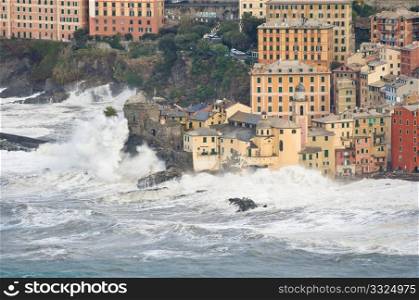 Waves break over the church and the castle in Camogli, Italy