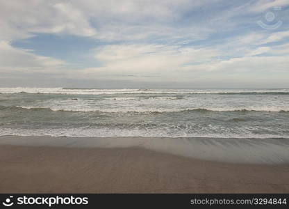 Waves breaking on the beach under a cloudy blue sky