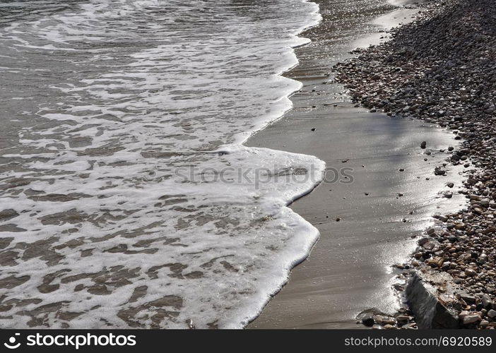 Waves crashing on stone beach. Waters edge abstract sea background.