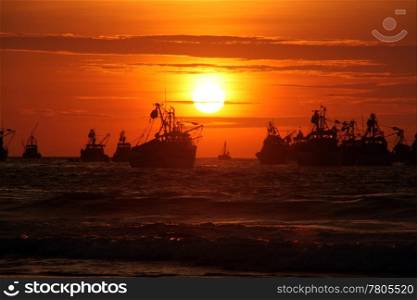Waves, fishing boats and sunset on the sea in Mancora, Peru