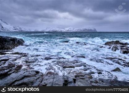 Waves of Norwegian sea crushing at rocky coast in fjord. Vikten, Lofoten islands, Norway. Norwegian Sea waves on rocky coast of Lofoten islands, Norway