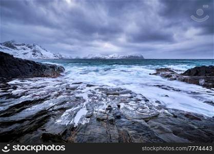 Waves of Norwegian sea crushing at rocky coast in fjord. Vikten, Lofoten islands, Norway. Norwegian Sea waves on rocky coast of Lofoten islands, Norway