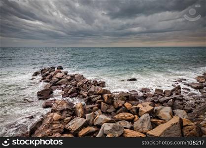 Waves of the Adriatic Sea crashing over an artificial cliff under stormy sky.