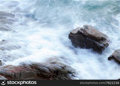 waves of the ocean crashing into the rocks. The wave washed rocks violently and continuously.