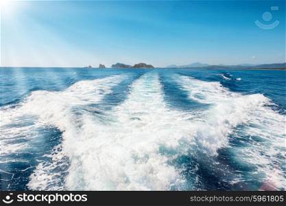 Waves on blue sea behind the speed boat water in sunny day with sun rays