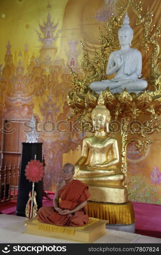 Wax monk and golden buddhas inside white temple near Chiang Rai, Thailand