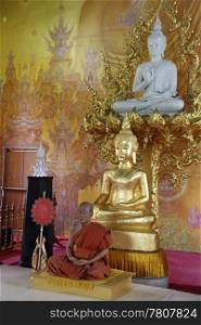 Wax monk and golden buddhas inside white temple near Chiang Rai, Thailand