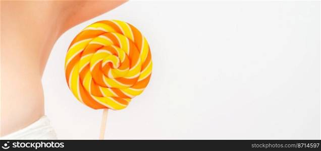 Waxing, depilation concept. A young female holds a round lollipop near her armpit on white background. Waxing, depilation concept. A young female holds a round lollipop near her armpit on white background.