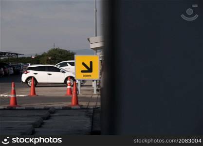 Way down - exit the building's parking lot with a sign down right arrow. Arrow sign in yellow and black high above from ground to direct the car in the right direction. Direction up and down for safet