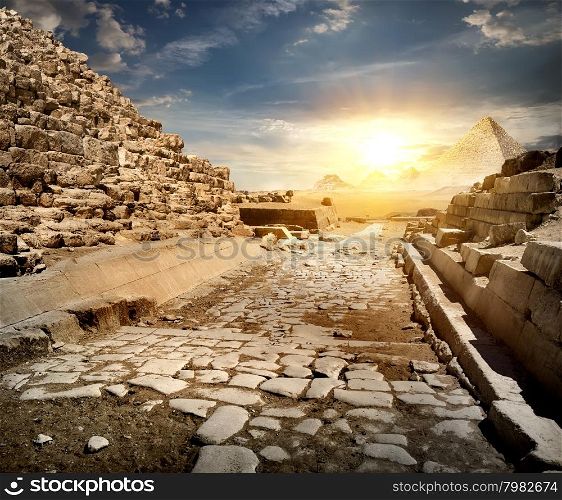 Way through ruins of egyptian pyramids and sun
