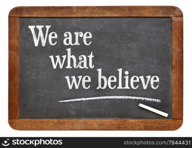 We are what we believe - text on a vintage slate blackboard