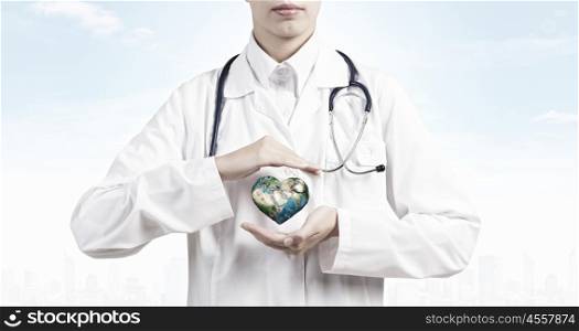 We treat with care. Close up of female doctor holding Earth planet in hands. Elements of this image are furnished by NASA