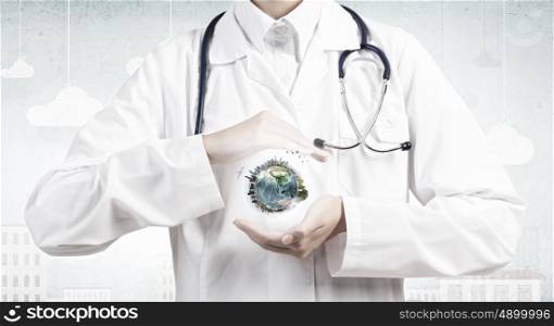 We treat with care. Close up of female doctor holding Earth planet in hands. Elements of this image are furnished by NASA