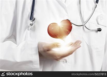 We treat with love and care. Close view of female doctor holding with care red heart