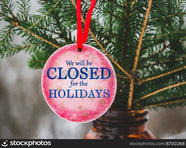 We will be closed for the Holidays. Beautiful signboard for Christmas and New Year holidays. Colorful Christmas balls on the background of the Christmas tree. Closeup, top view. Holidays concept. We will be closed for the Holidays