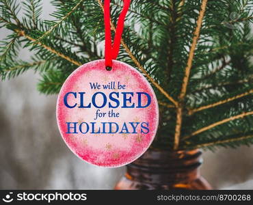 We will be closed for the Holidays. Beautiful signboard for Christmas and New Year holidays. Colorful Christmas balls on the background of the Christmas tree. Closeup, top view. Holidays concept. We will be closed for the Holidays