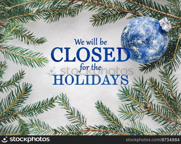 We will be closed for the Holidays. Beautiful signboard for Christmas and New Year holidays. Colorful Christmas balls on the background of the Christmas tree. Closeup, top view. Holidays concept. We will be closed for the Holidays