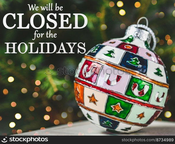 We will be closed for the Holidays. Beautiful signboard for Christmas and New Year holidays. Colorful Christmas balls on the background of the Christmas tree. Closeup, top view. Holidays concept. We will be closed for the Holidays