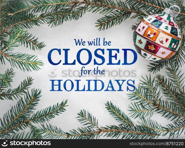 We will be closed for the Holidays. Beautiful signboard for Christmas and New Year holidays. Colorful Christmas balls on the background of the Christmas tree. Closeup, top view. Holidays concept. We will be closed for the Holidays