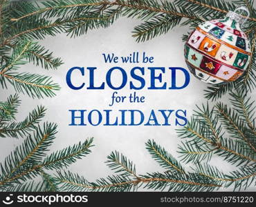 We will be closed for the Holidays. Beautiful signboard for Christmas and New Year holidays. Colorful Christmas balls on the background of the Christmas tree. Closeup, top view. Holidays concept. We will be closed for the Holidays